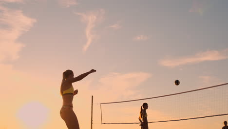 An-Einem-Schönen-Sommerabend-Springt-Ein-Sportliches-Mädchen-Beim-Beachvolleyball-In-Die-Luft-Und-Schlägt-Den-Ball-über-Das-Netz.-Eine-Kaukasische-Frau-Erzielt-Einen-Punkt.